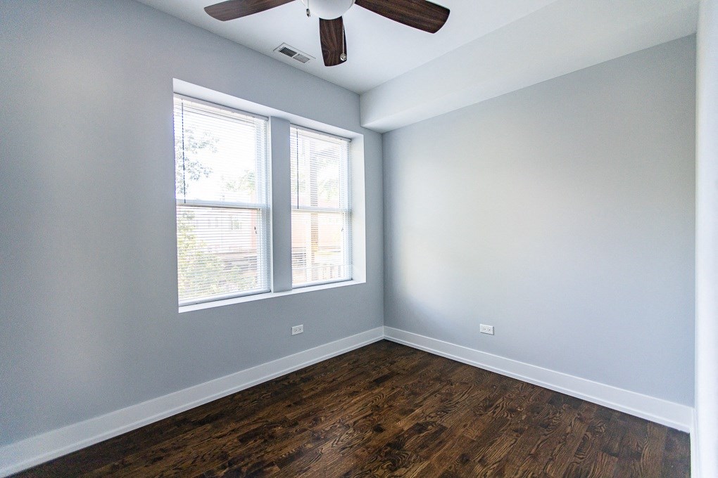 an empty room with wood floors and a ceiling fan