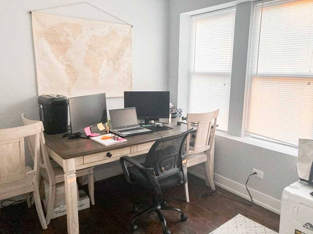 a desk with two computers and a map on the wall