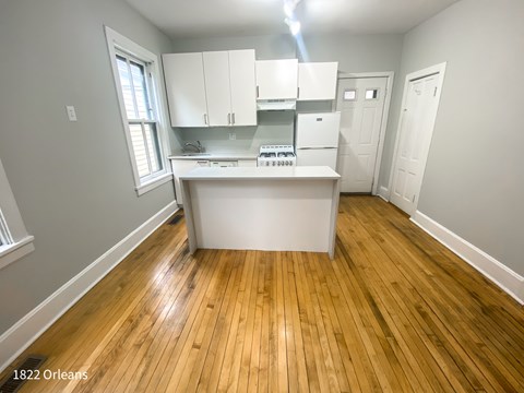 A kitchen with white cabinets and a wooden floor.