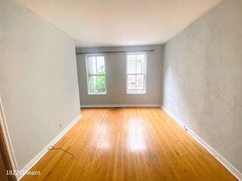A room with wooden floors and two windows.