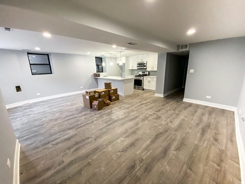 A room with wooden flooring and boxes on the floor.