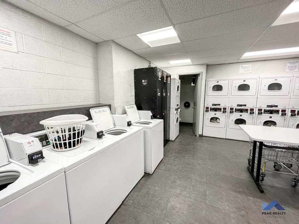a laundry room with washers and dryers and a table with a laundry basket