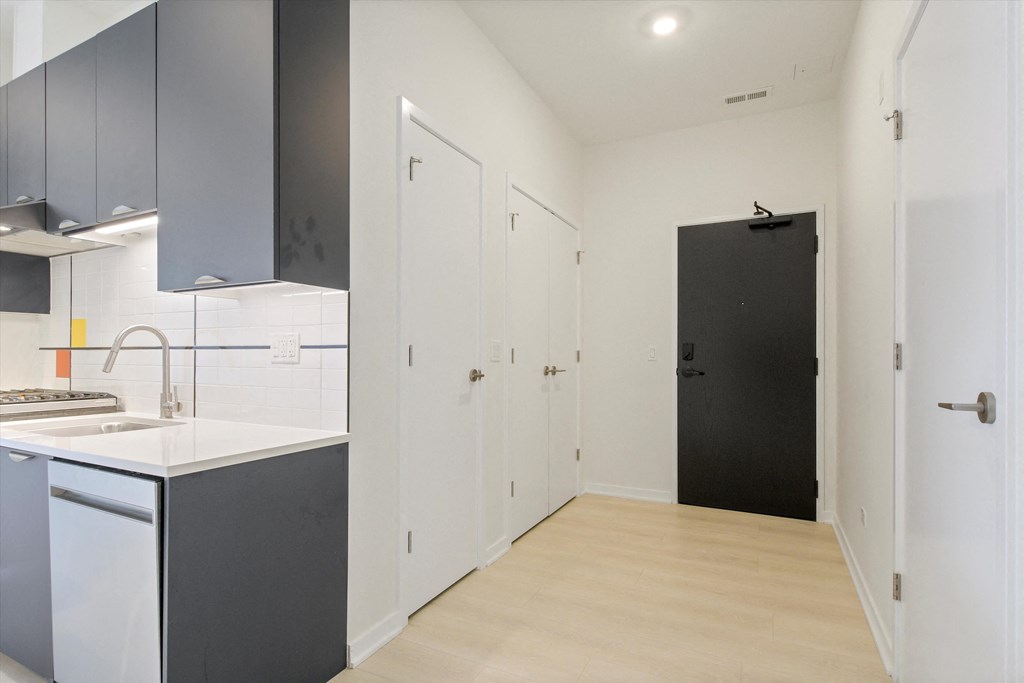 a renovated kitchen with white cabinets and a black door