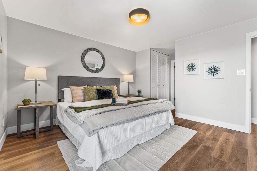 a bedroom with a bed and white walls and wood floors