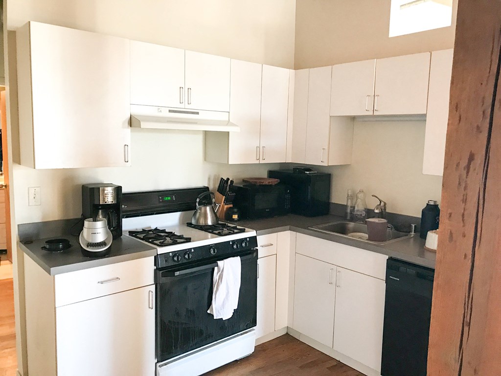 a kitchen with white cabinets and a stove and a sink