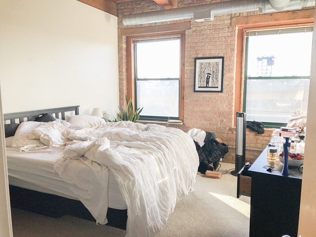 a bedroom with a bed and a brick wall