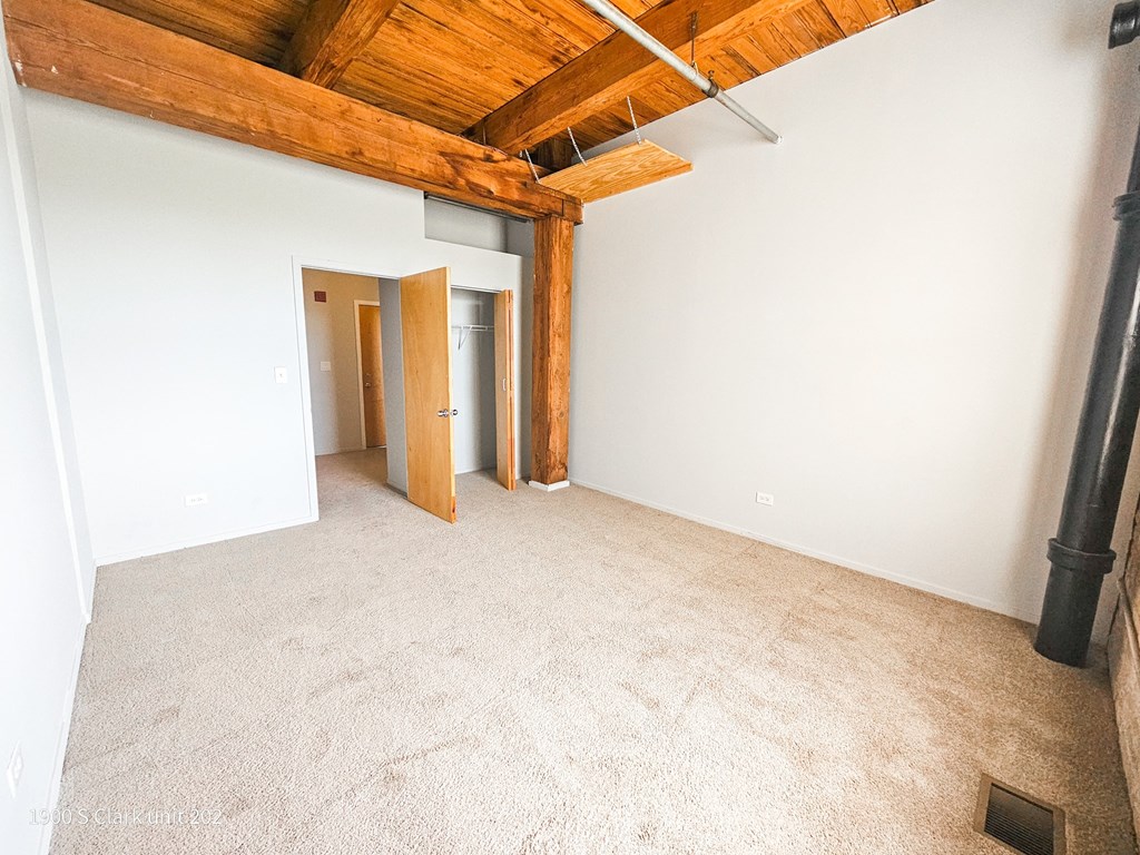 an empty living room with white walls and a wood ceiling