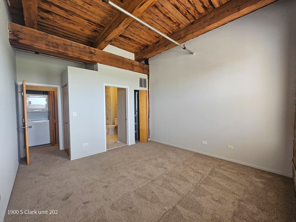 a room with a carpeted floor and a ceiling with wooden beams