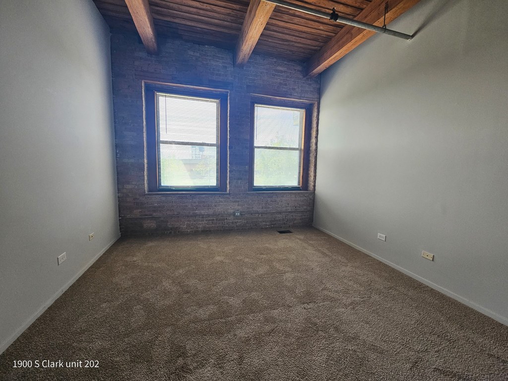 a room with a carpeted floor and two windows