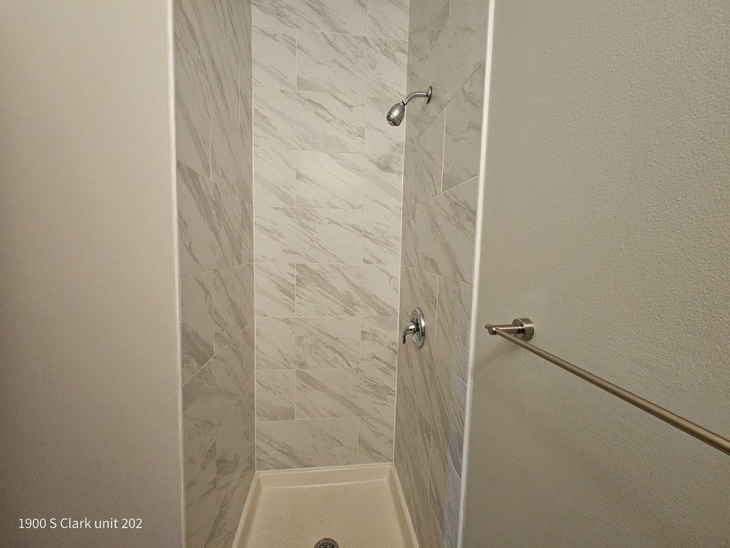 a walk in shower in a white marble bathroom