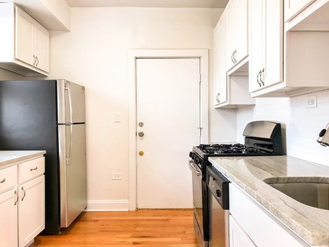 A kitchen with a black fridge and stove top oven.