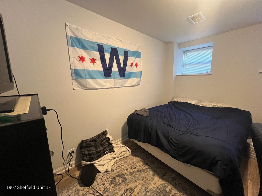 a small bedroom with a bed and a w flag on the wall