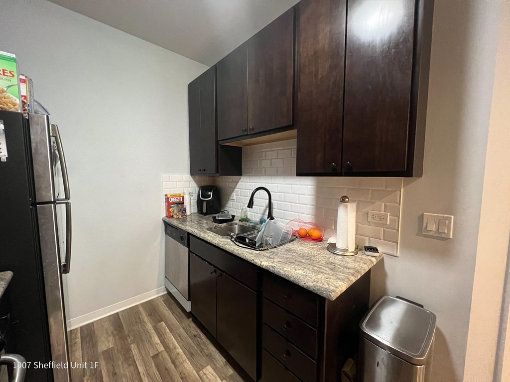 a kitchen with dark cabinets and a counter with a sink and a refrigerator