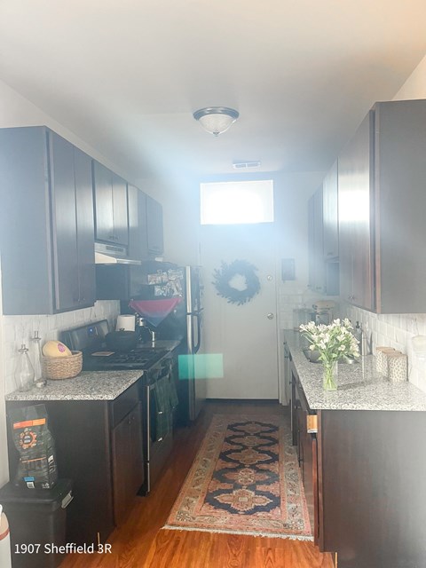 A kitchen with dark wood cabinets and a rug on the floor.