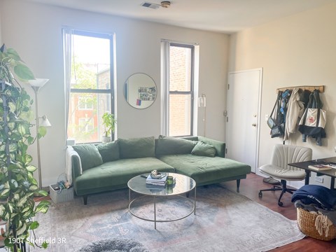 A living room with a green couch and a glass table.