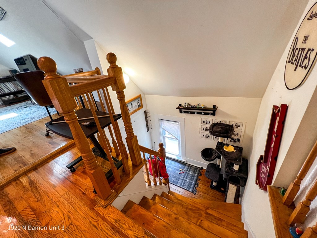 the view from the top of the stairs looking down into the living room and kitchen
