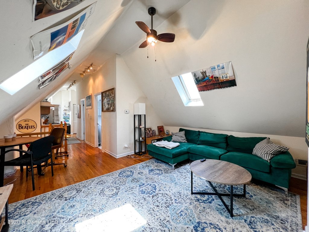 a living room with a green couch and a ceiling fan