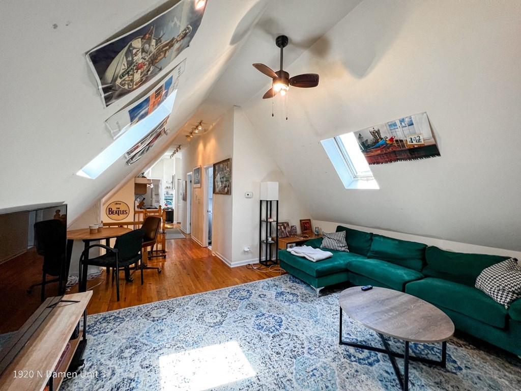 a living room with a green couch and a ceiling fan