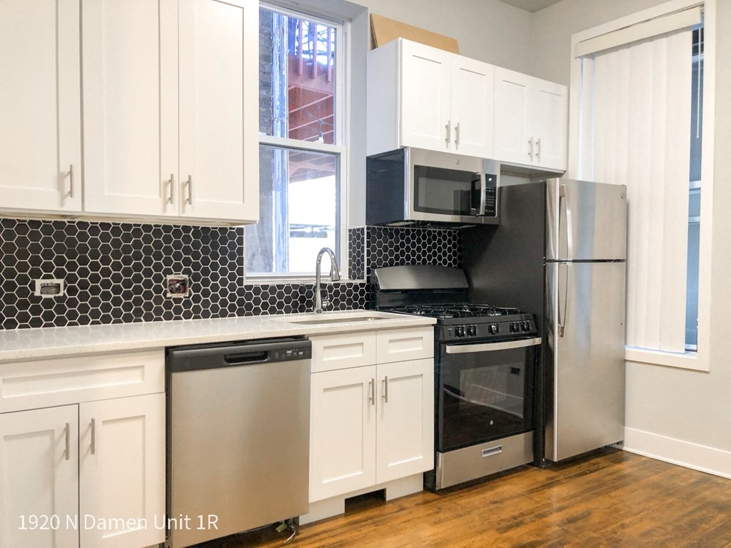 a kitchen with white cabinets and black and white appliances