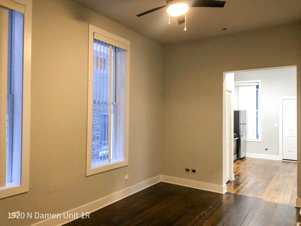 an empty living room with wood floors and a large window