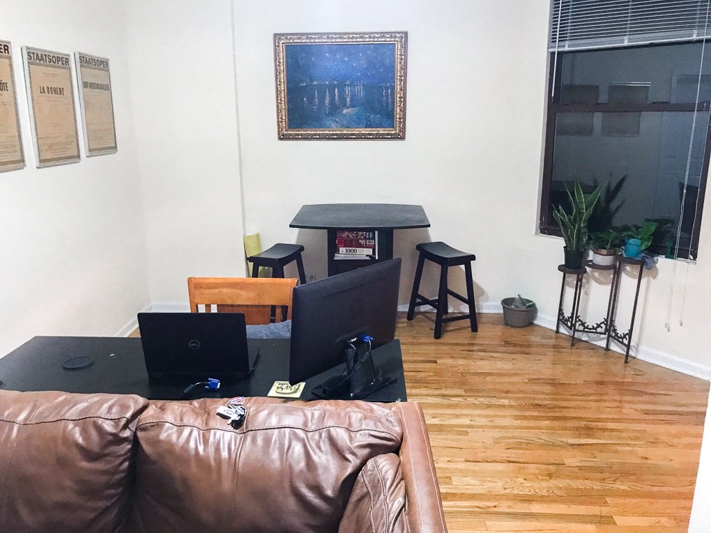 a living room with a leather couch and a table with two laptops