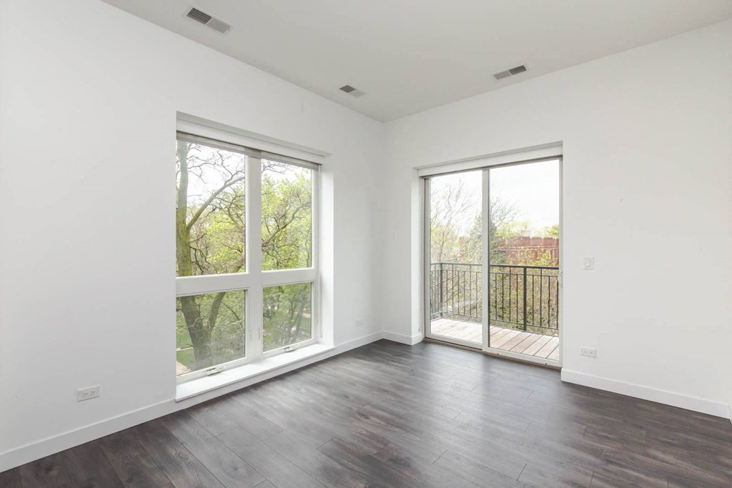 an empty living room with wood floors and large windows