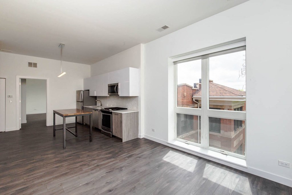 a living room with a large window and a kitchen