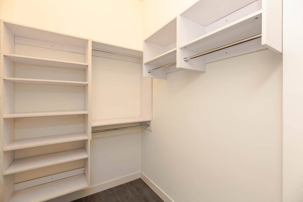a walk in closet with white shelves and