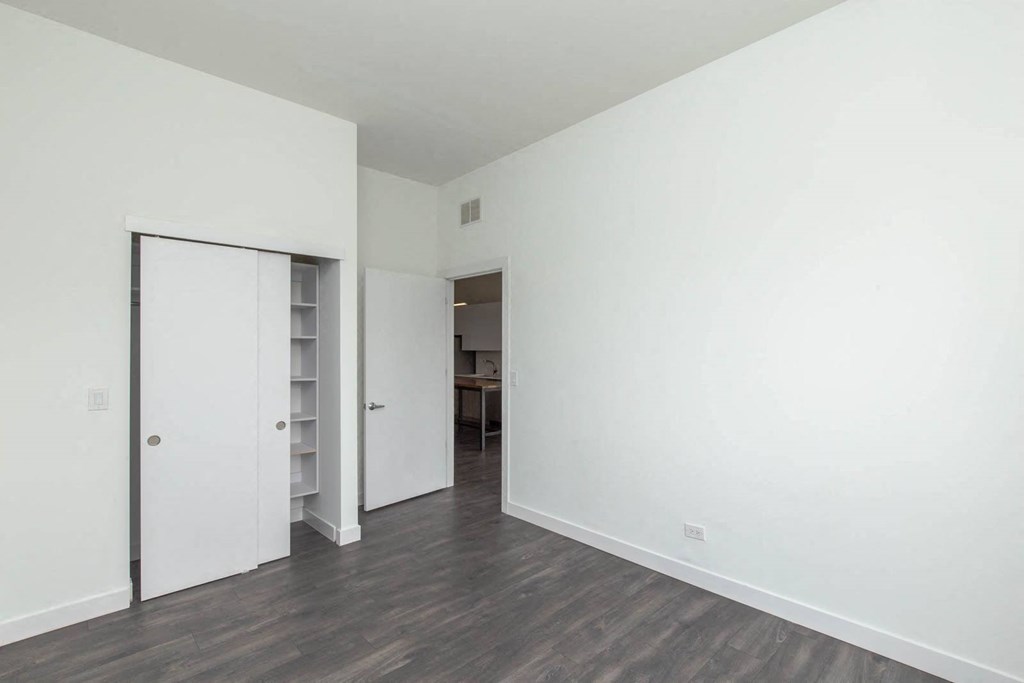 a bedroom with white walls and a door to a closet