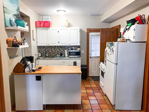 A kitchen with a refrigerator, oven, and sink.