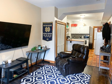 A living room with a black leather chair and a TV.