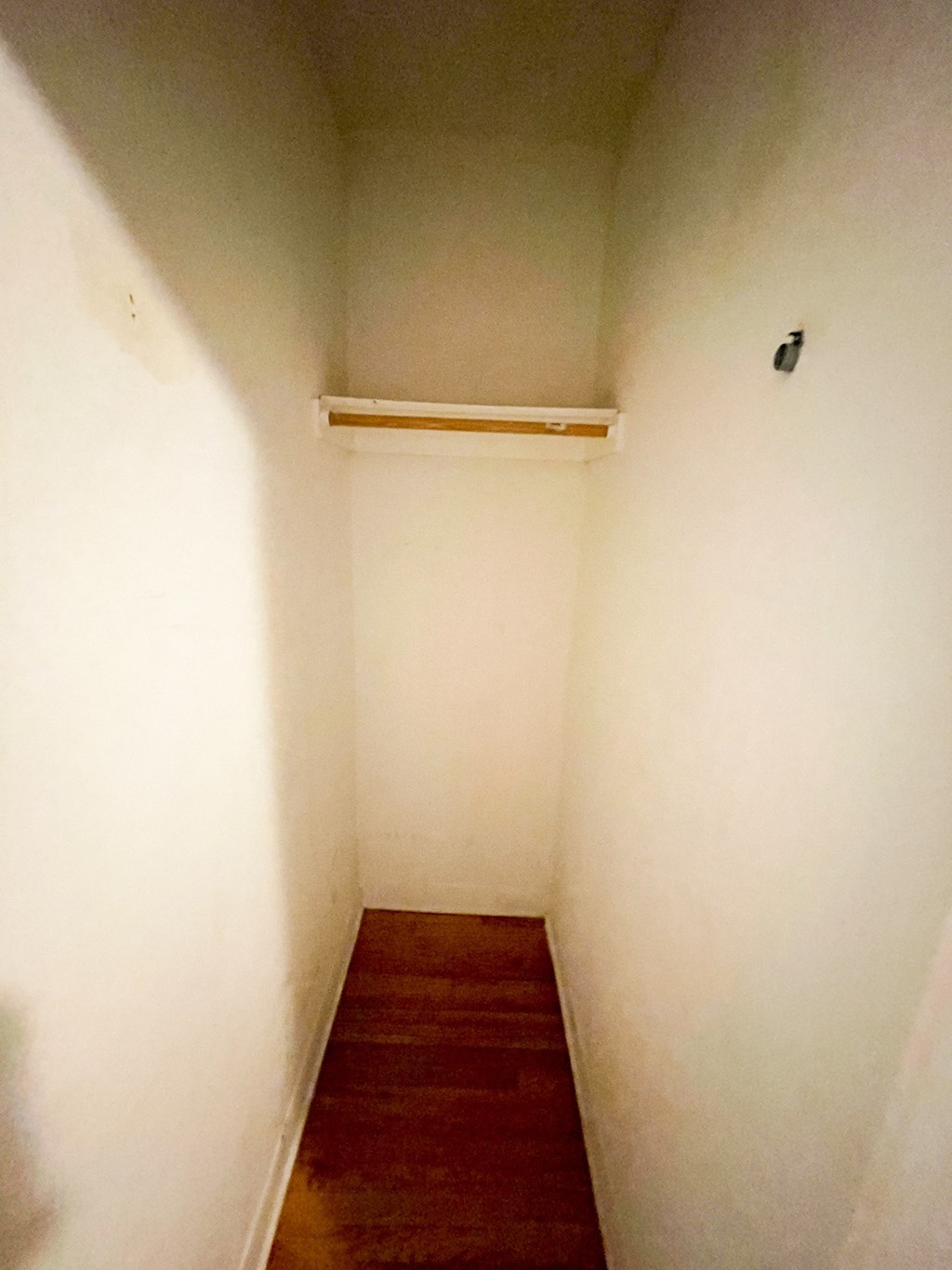 A long, narrow hallway with a wooden floor and white walls.