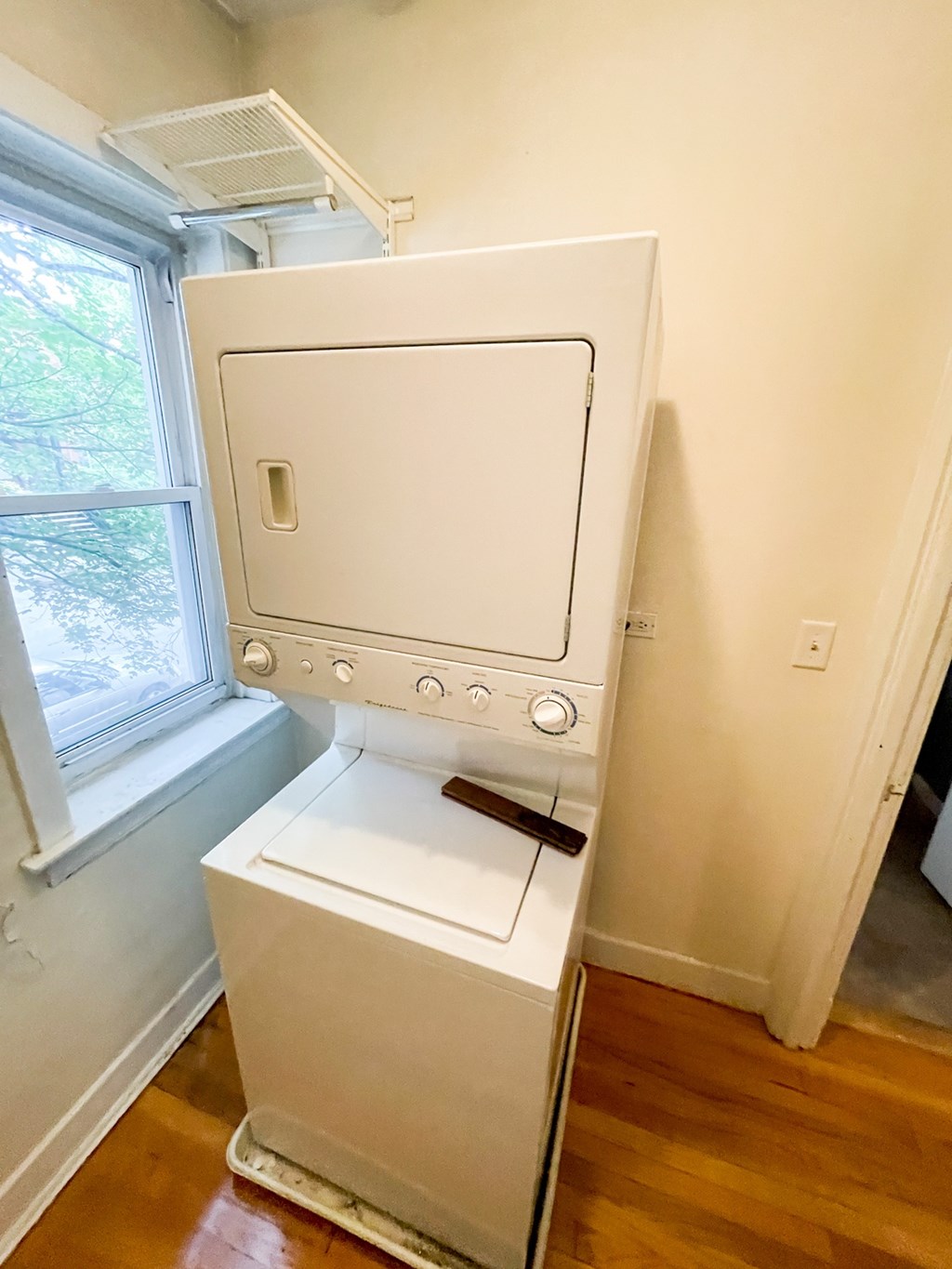 A white washing machine in a room with wooden flooring.