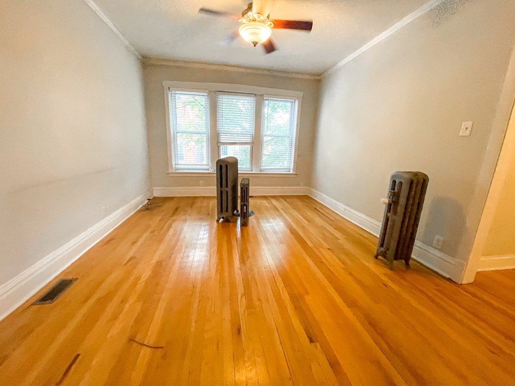 A room with wooden floors and a ceiling fan.