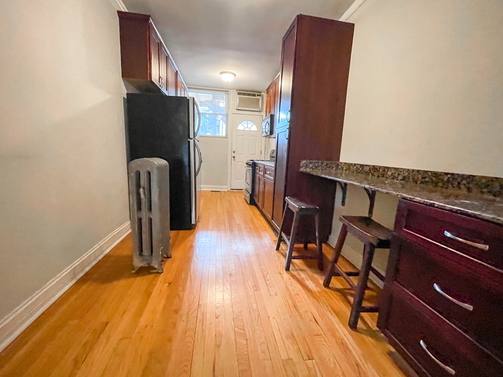 A kitchen with a black fridge and wooden floors.