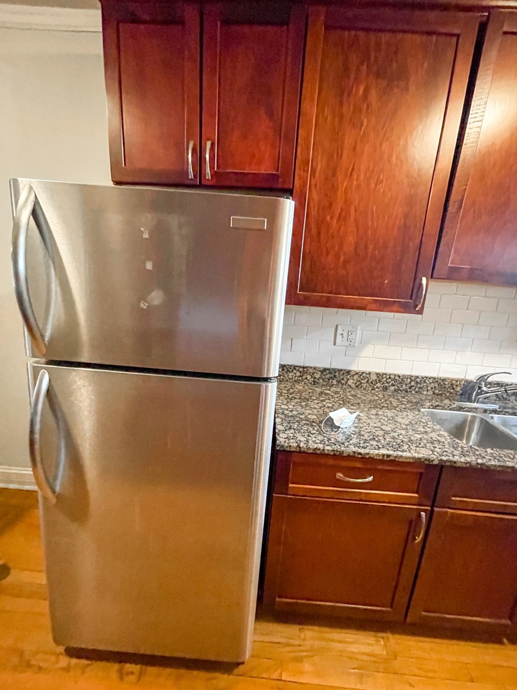 A silver refrigerator stands in a kitchen with wooden cabinets.