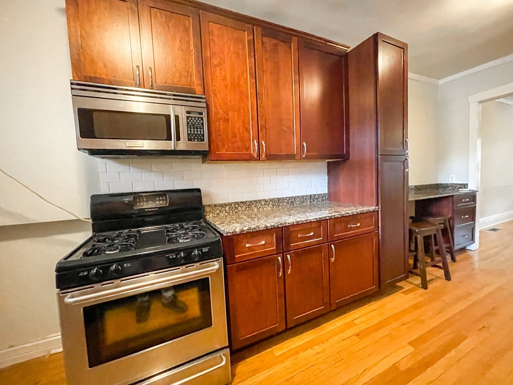 A kitchen with a stove, microwave, and cabinets.
