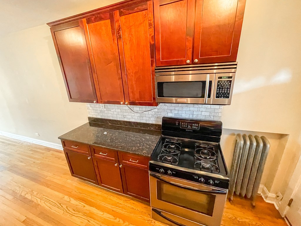 a kitchen with wooden cabinets and a stove and a microwave