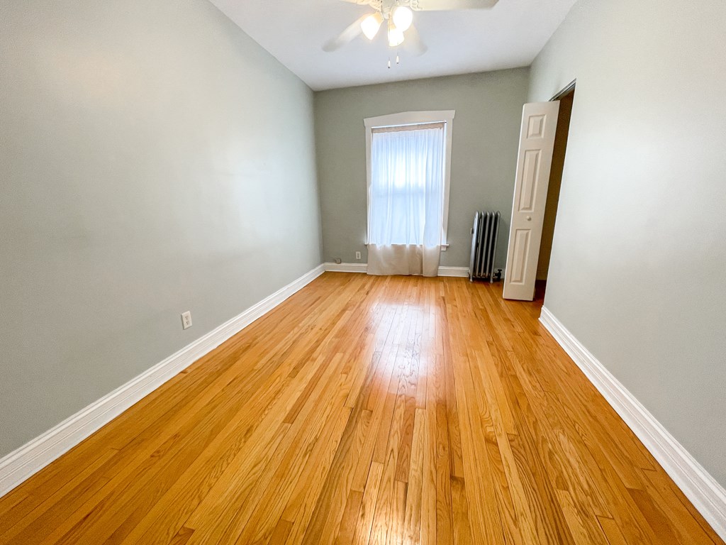 an empty living room with wood floors and a window