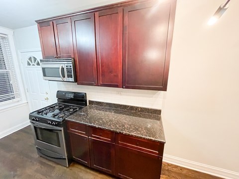 A kitchen with dark wood cabinets and a black stove top oven.