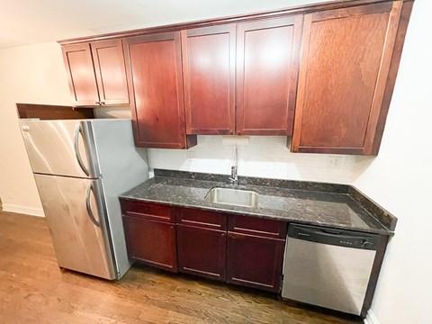 A kitchen with wooden cabinets and a stainless steel refrigerator.