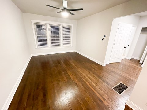 A room with a ceiling fan and wooden flooring.