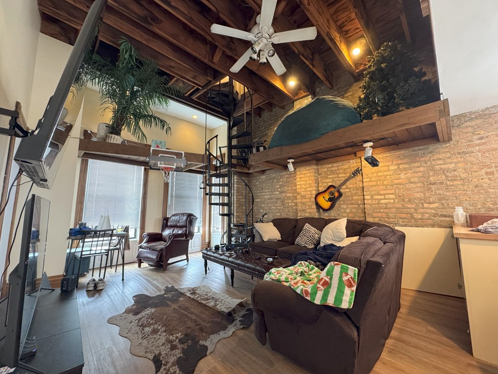 A living room with a brown couch and a ceiling fan.