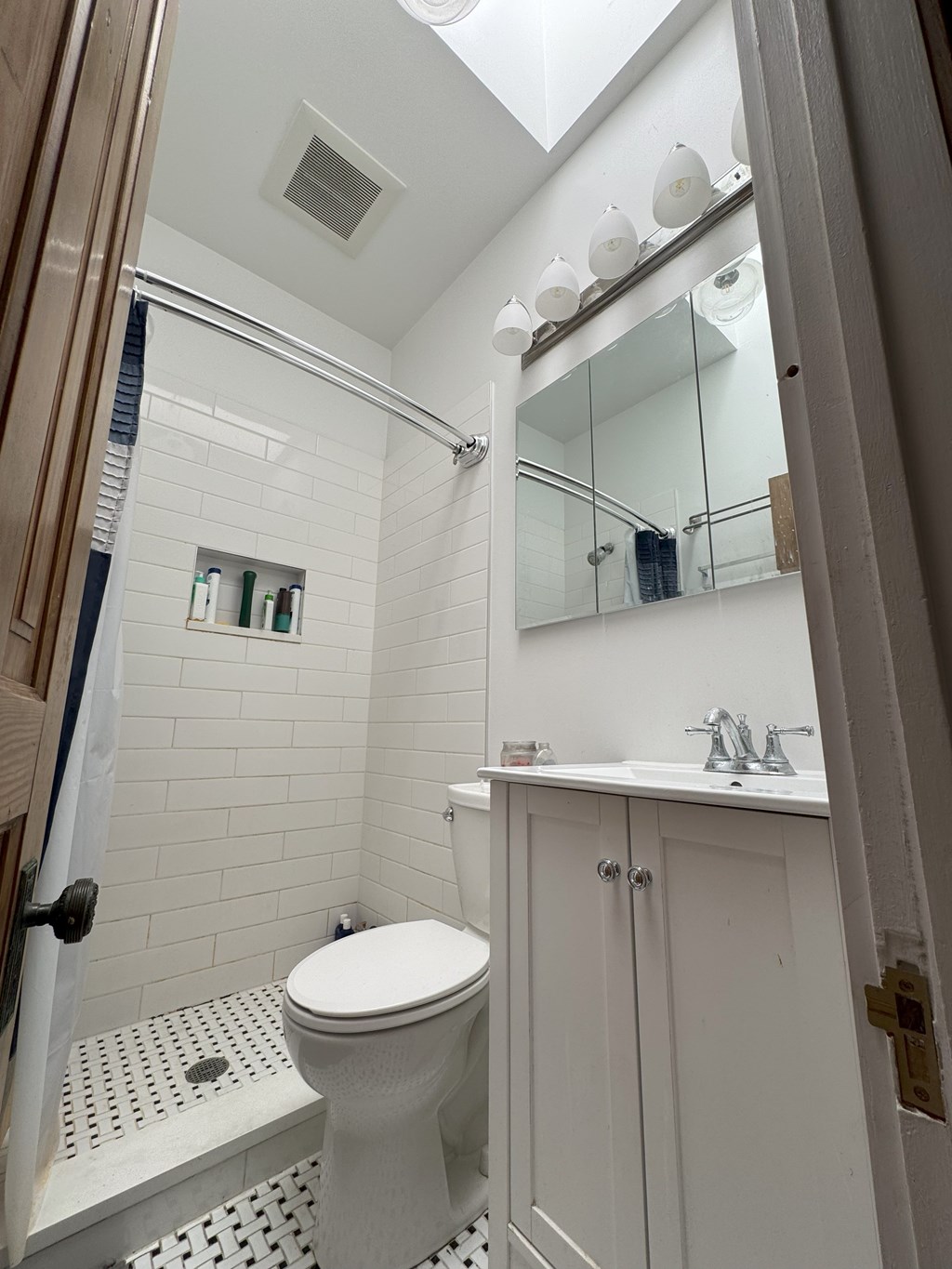A white toilet in a bathroom with a white tiled shower.