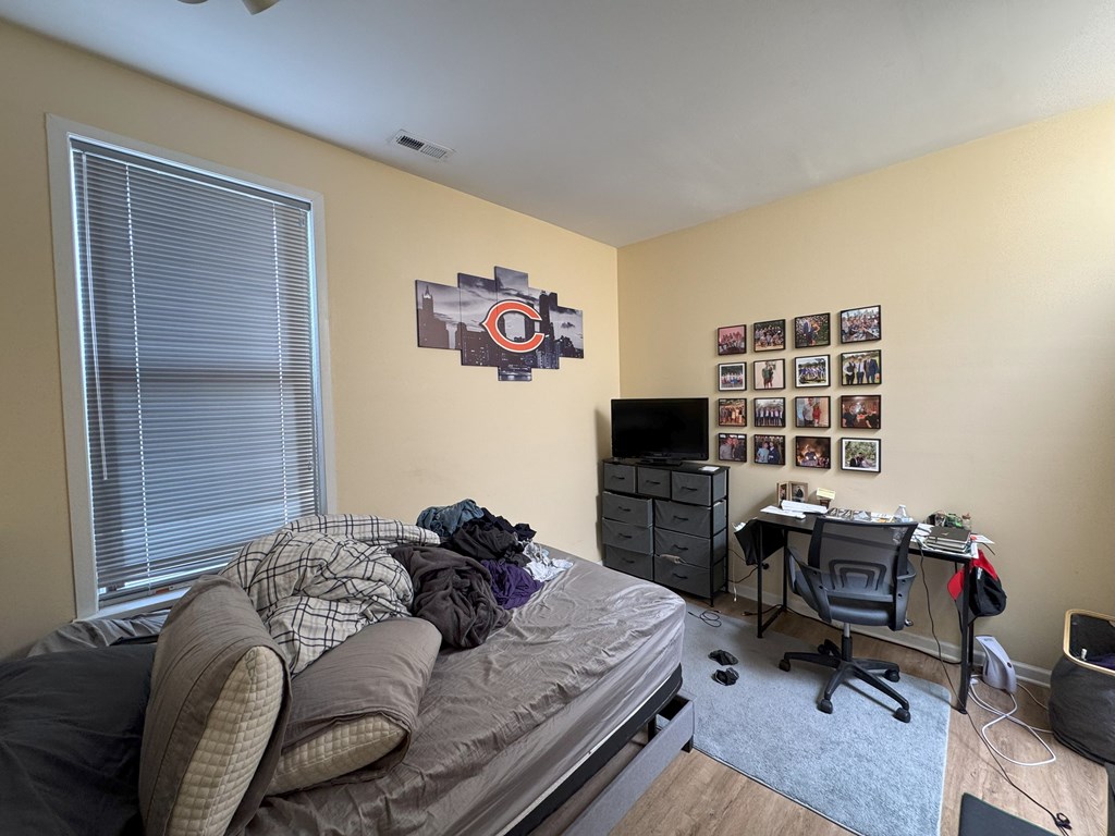 A bedroom with a bed, desk, and a wall with a Cubs logo.