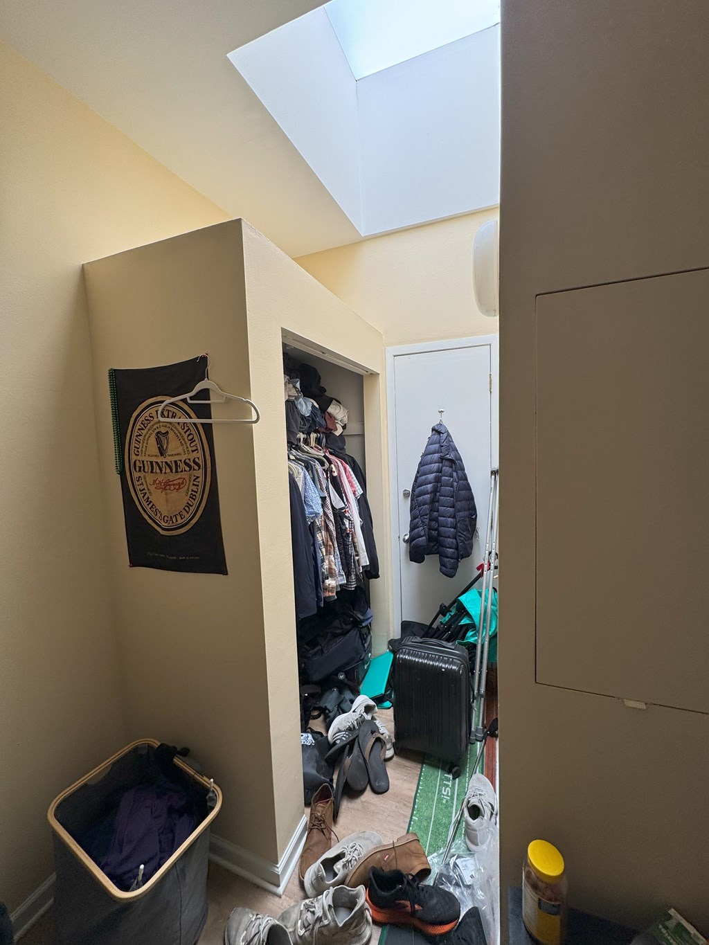 A small closet with a Guinness sign hanging on the wall.