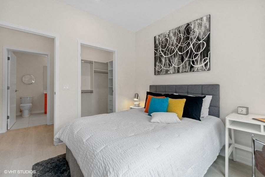 a white bedroom with a large bed and a bathroom