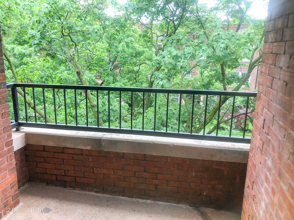a balcony with a view of trees and a brick wall