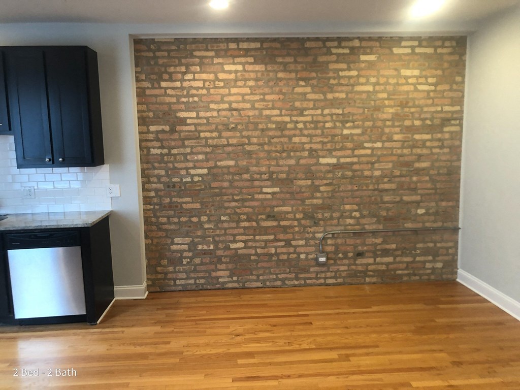 a brick wall in an empty room with wooden floors