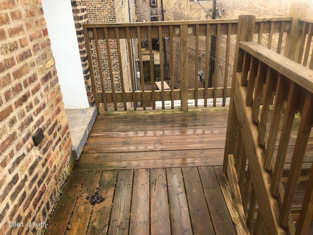 a balcony with wooden floors and a brick wall